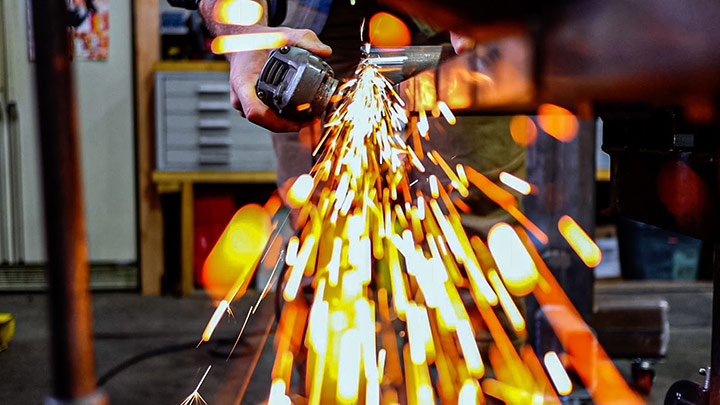 Artisan grinding metal with sparks flying