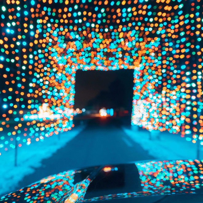 Car driving through a tunnel of blue and orange Christmas lights